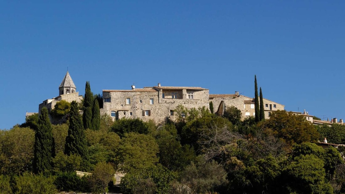 Quel village perché de la Drôme abrite une église romane avec une abside à l'ouest ?