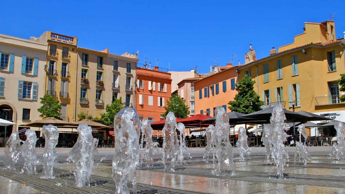 Quelle cité abrite à la fois une forteresse catalane, des thermes romains et un festival de photojournalisme ?